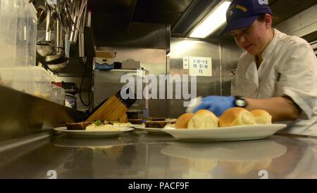 Petty Officer 2nd class Jenna Gros, ein Food Service Spezialisten an Bord USCGC Kukui (WLB 203), bereitet die Platten für ein Abendessen der Mitglieder und Beamten in die Wardroom Soldaten, 12. März 2016. Jede Woche trug Crewmitglieder sind zu einer Familie eingeladen - Abendessen mit leitenden Beamten. (U.S. Coast Guard Foto von Petty Officer 2. Klasse Melissa E. McKenzie/Freigegeben) Stockfoto