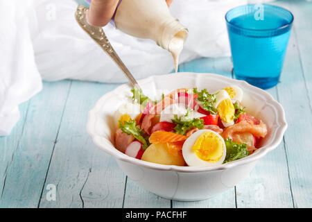 Dressing Salat gekochte Kartoffeln, Eier, geräucherten Lachs, Cherry Tomaten und Kopfsalat. Stockfoto