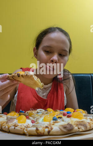 Jungen gemischten Rennen tween Girl essen Süßigkeiten, Eibisch, und Schokolade, Pizza, Lecken der Lippen Stockfoto
