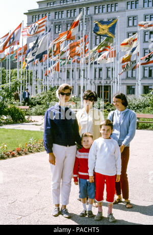 Amerikanische Touristen-Familiengruppe mit Mutter und Jungen und zwei jungen Frauen vor Esso-Haus mit deutschen Firmenflaggen, Neuer Jungfernstieg, Hamburg, in den 1960er Jahren Stockfoto