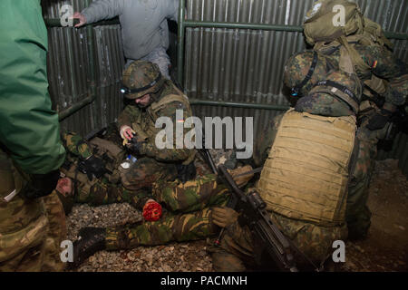 German Medical Soldaten vorher Combat casualty Care als Antwort auf eine simulierte Sprengkörper während Tactical Combat Casualty Care Kurs improvisiert, dass multinationale Soldaten aus NATO-Ländern die Teilnahme an der internationalen Special Training Center Train the Trainer Kurs, in dem die Hälfte der Teilnehmer Tactical combat Casualty care Lernen und die andere Hälfte Lernen, die Bekämpfung der Unfall- Kurs zu unterrichten. Das Training wurde von General Staufer Kaserne, 16. März 2016 durchgeführt. (U.S. Armee Foto von visuellen Informationen Spezialist Martin Greeson/Freigegeben) Stockfoto