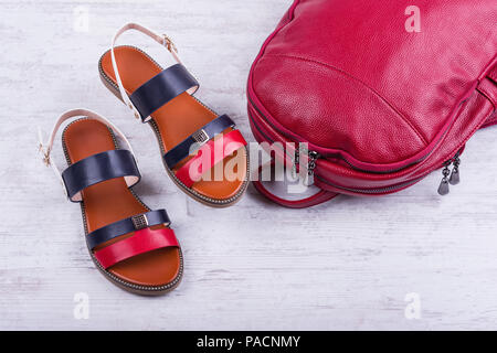 Der modische Frauen Sandalen und Rucksack auf weißem Holz- Hintergrund. Stockfoto