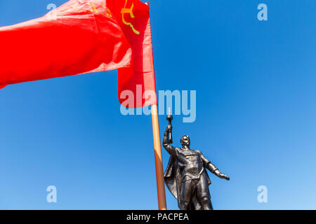 Denkmal für die sowjetischen Soldaten mit einer Maschinenpistole in der Hand eines Teilnehmers im Zweiten Weltkrieg mit der roten Flagge UDSSR. Stockfoto