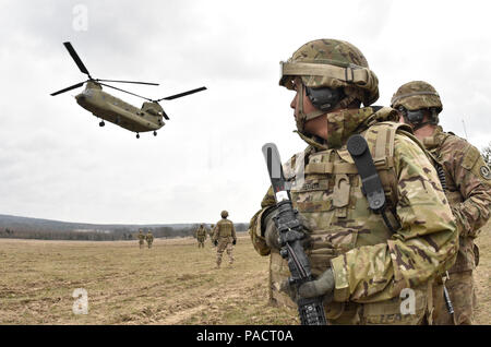 Sgt. Engel Peralta (vorne rechts), eine Kanone Crew Mitglied zu Archer Batterie, Field Artillery Squadron, 2.Kavallerie Regiment zugeordnet, wartet, wie er und seine Kollegen Troopers bereiten Sie eine CH-47 Chinook Hubschrauber Platine aus dem 12 Combat Aviation Brigade (Hubschrauber Loslösung) während der M777 Haubitze schlinge Ladevorgänge seiner Einheit an der Grafenwöhr Training Area durchgeführt, in der Nähe der Rose Barracks, Deutschland, 23. März 2016. Ziel der Veranstaltung war die Artillerie Tabelle II Training beim Helfen Arbeiten zwischen 2 CR-Field Artillery Squadron und der 12 CAB zu etablieren. (U.s. Stockfoto