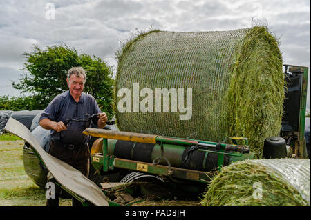 Ballydehob, West Cork, Irland. 22. Juli, 2018. Hollum basierte Landwirt Noel Ward wraps Silage querhölzer auf einem anderen sehr heißen Tag in Irland. Das Wetter ist wechselhaft im Laufe der nächsten Tage mit Regen Prognose für die ganze Woche. Die Temperaturen an den hohen Teens fallen/Low 20 Celsius. Credit: Andy Gibson/Alamy Leben Nachrichten. Stockfoto