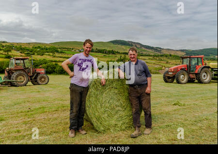 Ballydehob, West Cork, Irland. 22. Juli, 2018. Hollum basierte Bauern Michael Pat Ward und Noel Ward wrap Silage querhölzer auf einem anderen sehr heißen Tag in Irland. Das Wetter ist wechselhaft im Laufe der nächsten Tage mit Regen Prognose für die ganze Woche. Die Temperaturen an den hohen Teens fallen/Low 20 Celsius. Credit: Andy Gibson/Alamy Leben Nachrichten. Stockfoto