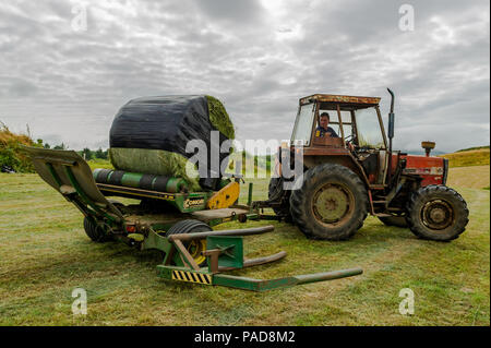 Ballydehob, West Cork, Irland. 22. Juli, 2018. Hollum basierte Landwirt Noel Station wickelt eine silage Kaution auf einem anderen sehr heißen Tag in Irland. Das Wetter ist wechselhaft im Laufe der nächsten Tage mit Regen Prognose für die ganze Woche. Die Temperaturen an den hohen Teens fallen/Low 20 Celsius. Credit: Andy Gibson/Alamy Leben Nachrichten. Stockfoto