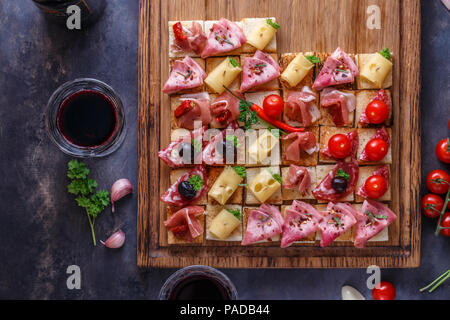 Lecker herzhaften Tomatensauce italienische Vorspeisen, oder Bruschetta, gerösteten Baguette mit Schinken, Schinken auf einem Holzbrett gekrönt Stockfoto