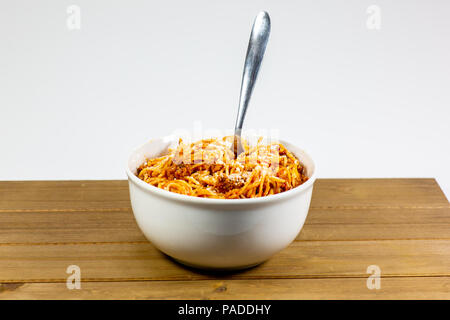 Spaghetti Bolognese in einem tiefen weiße Schüssel auf dem hölzernen Küchentisch warten gegessen zu werden. Stockfoto