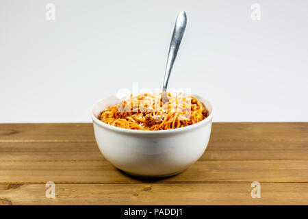 Spaghetti Bolognese in einem tiefen weiße Schüssel auf dem hölzernen Küchentisch warten gegessen zu werden. Stockfoto