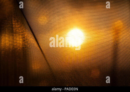 Glühende durch die Vorhänge des Hauses die Sonne bei Sonnenuntergang, orange Farbe aus der Brechung der Lichtstrahlen Stockfoto