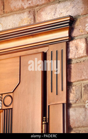 Element einer hölzernen Tür braun gefärbt in der klassischen geometrischen Stil mit goldenen Scharniere an der Mauer Hintergrund geschnitzt Stockfoto