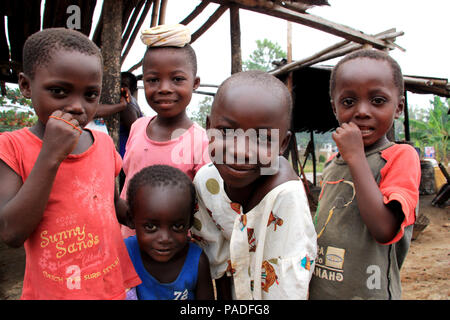 Blick auf neugierige afrikanische Kinder, die sich in einer Palmöl-Produktionsstätte in der Nähe von Cape Coast in Ghana versammeln und die Kamera betrachten Stockfoto