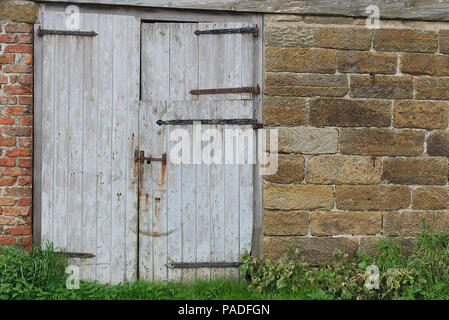 Rustikale Alte hölzerne Scheune Türen auf einem Bauernhof im späten Frühling im Norden von England, Yorkshire. Holz Textur Hintergrund. Stockfoto