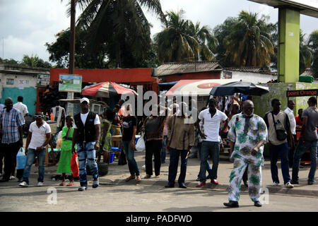 Afrikanische Menschen warten auf den Bus vor einigen Marktständen und Minimärkte in Abidjan, Côte d'Ivoire Stockfoto