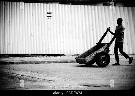 Afrikanischer Mann drückt seine Hand Warenkorb auf den Markt in Abidjan, Côte d'Ivoire Stockfoto