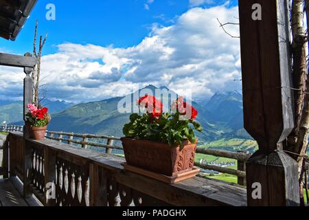 Schöne Topfpflanzen roten Geranien auf dem Balkon mit Blick auf ein Tal in den Kitzbüheler Alpen, Österreich Stockfoto