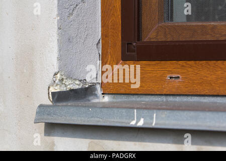 Nahaufnahme Ecke detail weiß verputzte Hauswand mit installierten neuen braunen Kunststoff Fenster mit Moskitonetz und Aluminium Fensterbank. Moderne Technol Stockfoto