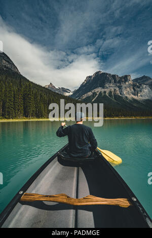 Junger Mann Kanufahren auf dem Emerald Lake in den Rocky Mountains, Kanada mit Kanu und die Berge im Hintergrund blaue Wasser. Stockfoto