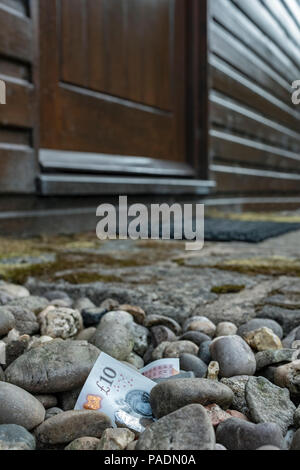 Geld in Form von einer Bank Hinweis auf dem Boden außerhalb eines Hauses. Stockfoto