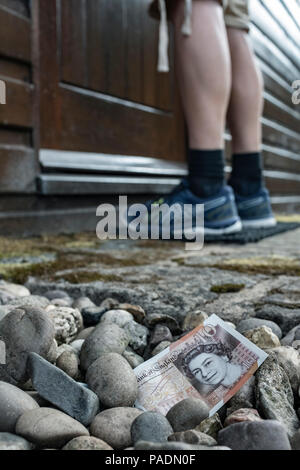 Geld in Form von einer Bank Hinweis auf dem Boden außerhalb eines Hauses. Stockfoto