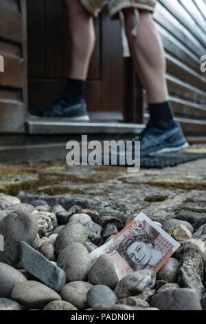 Geld in Form von einer Bank Hinweis auf dem Boden außerhalb eines Hauses. Stockfoto