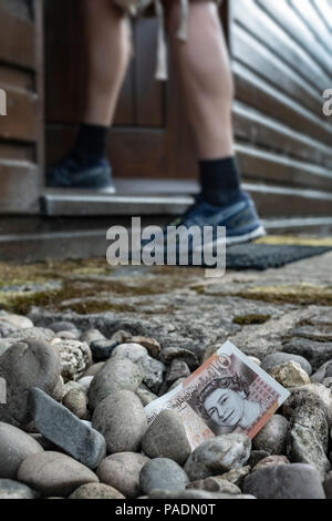 Geld in Form von einer Bank Hinweis auf dem Boden außerhalb eines Hauses. Stockfoto