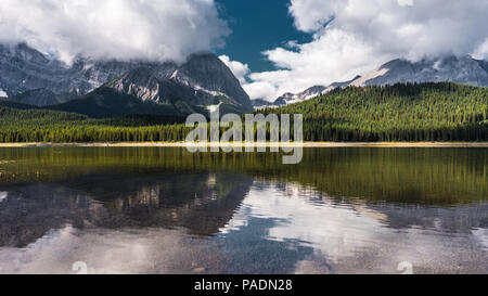 Reflexion mit See und Bergen niedrig hängenden couds im Lower Kananaskis See von Peter Lougheed Provincial Park Kananaskis Country Alberta Kanada Stockfoto