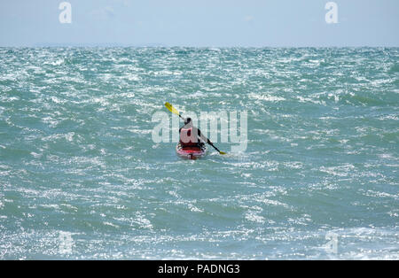 Mann mit Schwimmweste paddeln sein Kajak in stürmische See vor der Küste von East Preston, West Sussex, UK. Richtung Osten nach Westen. Stockfoto