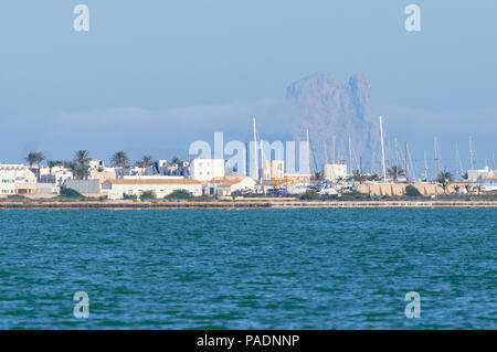 La Savina Ansicht mit Segel Schiffe Masten in Port mit Es Vedrá Inselchen im Hintergrund vom Estany Pudent (Ses Salines Natural Park, Formentera, Spanien) Stockfoto