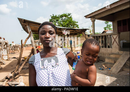 - PORTO NOVO, BENIN - Mar 8, 2012: Unbekannter beninischen Mutter trägt ihr Kind in ihren Händen Bevölkerung von Benin Leiden der Armut aufgrund der schwierigen Stockfoto