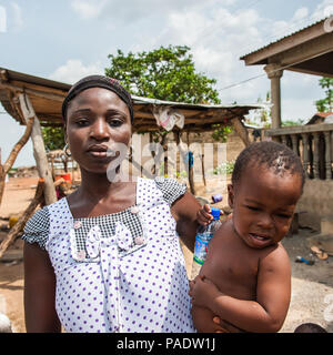 - PORTO NOVO, BENIN - Mar 8, 2012: Unbekannter beninischen Mutter trägt ihr Kind in ihren Händen Bevölkerung von Benin Leiden der Armut aufgrund der schwierigen Stockfoto