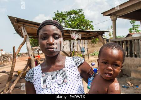 - PORTO NOVO, BENIN - Mar 8, 2012: Unbekannter beninischen Mutter trägt ihr Kind in ihren Händen Bevölkerung von Benin Leiden der Armut aufgrund der schwierigen Stockfoto