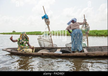 - PORTO NOVO, BENIN - Mar 9, 2012: Unbekannter Beninischen zwei Frauen Segel ein Fischerboot. Bevölkerung von Benin Leiden der Armut aufgrund der schwierigen wirtschaftlichen Stockfoto