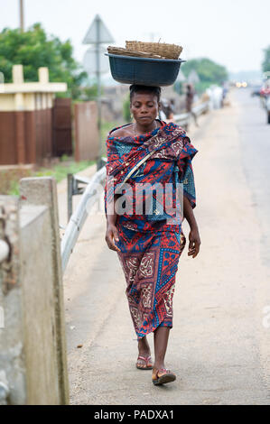 - PORTO NOVO, BENIN - Mar 9, 2012: Unbekannter beninischen Frau mit viel Material über den Kopf. Kinder von Benin Leiden der Armut aufgrund der schwierigen Stockfoto