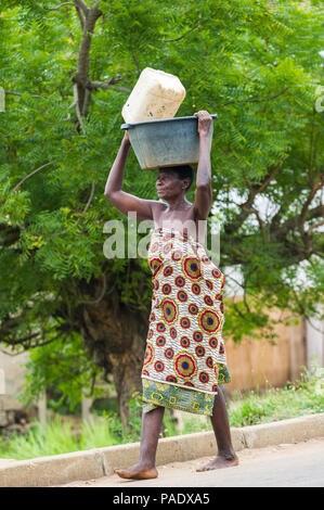 - PORTO NOVO, BENIN - Mar 9, 2012: Unbekannter beninischen Frau mit viel Material über den Kopf. Kinder von Benin Leiden der Armut aufgrund der schwierigen Stockfoto