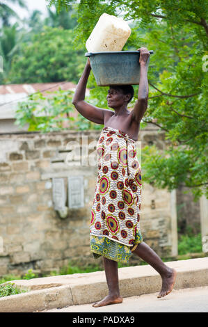 - PORTO NOVO, BENIN - Mar 9, 2012: Unbekannter beninischen Frau mit viel Material über den Kopf. Kinder von Benin Leiden der Armut aufgrund der schwierigen Stockfoto