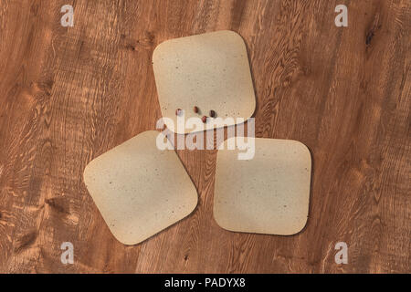 Drei quadratische vintage Achterbahnen und Kaffeebohnen auf Holz Hintergrund. 3D-Darstellung Stockfoto