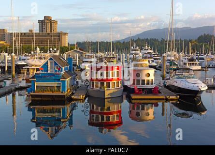 VANCOUVER, Kanada - 1. JULI 2017: Boot Häuser auf dem Wasser von Coal Harbour Marina bei Sonnenaufgang. Stadt Panorama mit schwebenden Bootshäuser, Wald, und moun Stockfoto