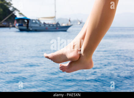 Weibliche Füße inmitten Schiff auf dem Meer. Rest auf einer Yacht. Eine junge Frau, die auf dem Sun sunbathes Stockfoto