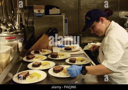 Petty Officer 2nd class Jenna Gros, ein Food Service Spezialisten an Bord USCGC Kukui (WLB 203), bereitet die Platten für ein Abendessen der Mitglieder und Beamten in die Wardroom Soldaten, 12. März 2016. Jede Woche trug Crewmitglieder sind zu einer Familie eingeladen - Abendessen mit leitenden Beamten. (U.S. Coast Guard Foto von Petty Officer 2. Klasse Melissa E. McKenzie/Freigegeben) Stockfoto