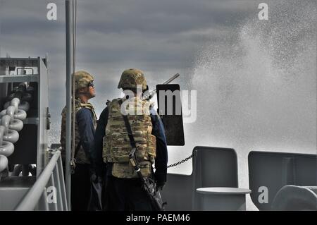 Armee Mariners mit der 1099Th Transport Loslösung der SP4 James A. Loux, Logistik Unterstützung Fahrzeug-6, sind durch eine Welle während der Durchführung einer Schlacht Station bohren während einer Mission in den Persischen Golf, 3. März 2016 spritzte. Alle Mitglieder des Schiffes werden ausgebildet, um eine Vielzahl von kleinen Waffen und Crew zu verwenden - Serviert Waffen für den Fall, dass das Boot ist angegriffen. Stockfoto