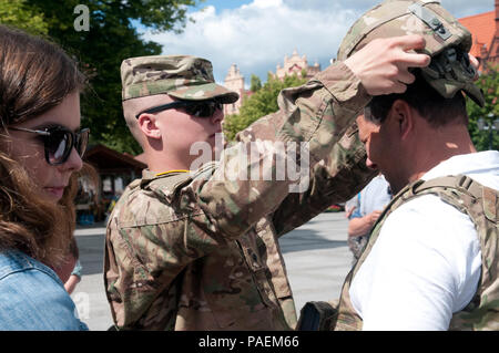 Spc. Patrick Dawson, von Peoria, Illinois, mit dem 18 Military Police Brigade hilft ein polnischer Staatsangehöriger, der verbesserte äußere taktische Weste und Armee bekämpfen Helm während der statische Anzeige don an eine multikulturelle Veranstaltung auf dem Marktplatz von Chelmno, Polen, als ein Teil der Übung Anakonda 2016. Übung Anakonda 2016 ist ein Premier, der Schulungsveranstaltung für die US-Armee Europa und den teilnehmenden Nationen und zeigt den USA und Partner Nationen können effektiv Einheit zusammen unter einem einheitlichen Kommando beim Training auf einem modernen Szenario. Stockfoto