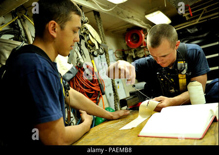 Coast Guard Cutter Eagle Crewmitglieder Seaman Marcus Cuenca und Seemann Devin Adams erlernt und übt die Kunst des Nähens Segel in Ihrer freien Zeit. Besatzungsmitglieder sind geschult auf See erlittene Schäden zu reparieren. U.S. Coast Guard Foto von Petty Officer 2. Klasse Matthew S. Masaschi. Stockfoto