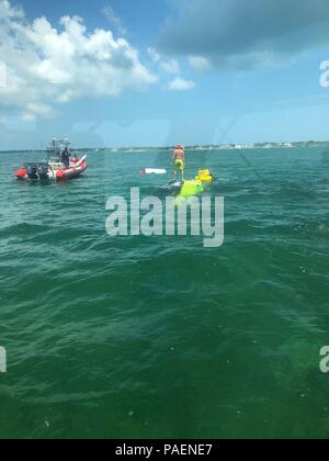 Eine kommerzielle Bergungsschiff nähert sich einem Gekenterten Boot mit zwei Personen am Samstag, 14. Juli 2018 in der Nähe von Walen Hafen in der Nähe der Islamorada. Ein Coast Guard Station Islamorada 33-Fuß-Special Purpose Handwerk - Strafverfolgung boatcrew die zwei Leute zog sich aus dem Wasser und von Verletzungen. U.S. Coast Guard Foto mit freundlicher Genehmigung der Station Islamorada Stockfoto