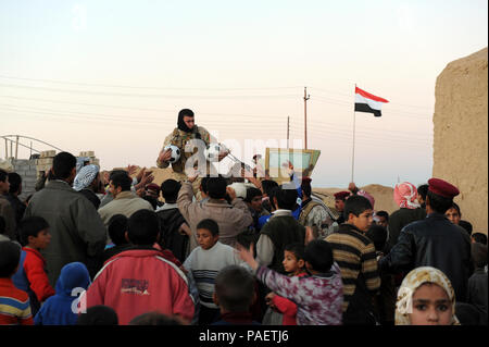 Ein Soldat aus der 1., 2., 15., 12., irakische Armee, Pässe, Spielzeug und Zubehör für Kinder im Dorf Morbat Algabha, Irak, Jan. 6, 2010. Us-Soldaten vom 1 Platoon, Bravo Truppe, 6 Staffel, 1.Kavallerie, 1st Brigade Combat Team, 1st Armored Division, und 1-15 IA geliefert Spielzeug und liefert in das Dorf, in dem Bemühen, eine gute Verbindung mit den Bürgern zu pflegen. Stockfoto