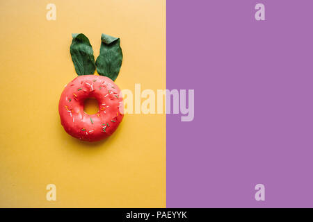 Eine kreative Donut mit Ohren der Blätter erinnert an ein Kaninchen auf einem farbigen Hintergrund in einem minimalistischen Stil. In der Nähe Platz für Text Stockfoto