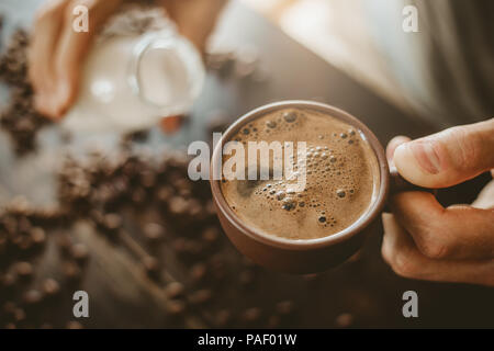 Junger Mann Kaffee mit Milch. Gießen Milch im Kaffee. Nahaufnahme Stockfoto