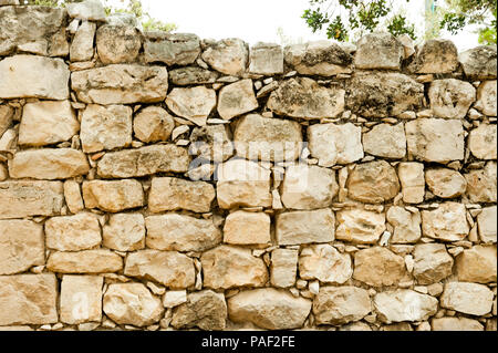 Die Wand ist von großen gehauenen Steinen ohne verbindliche Materialien Stockfoto