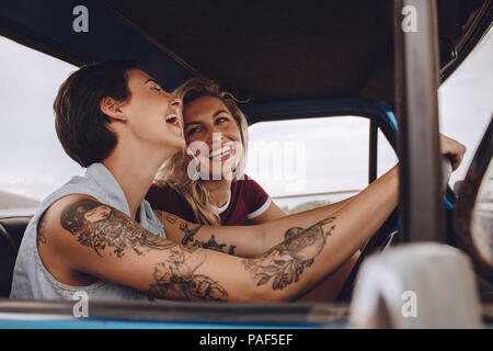 Glückliche junge Frauen Lachen und Genießen im Auto auf der Fahrt zu den Ferien. Mädchen, die Spaß auf der Reise. Stockfoto